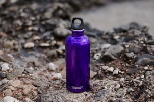 Purple water bottle surrounded by rocks