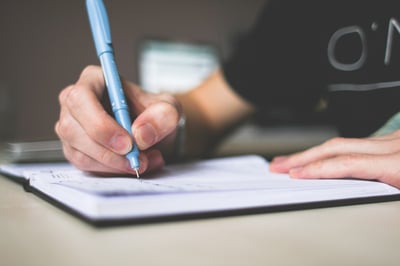 hand writing with blue pen in journal